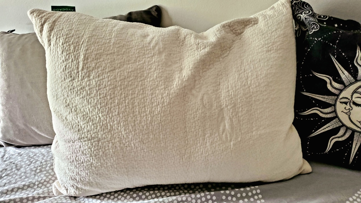 cream-colored pillow on a bed with other pillows