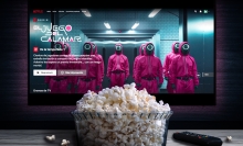 A tub of popcorn sits in front of a TV playing Netflix's "Squid Game."