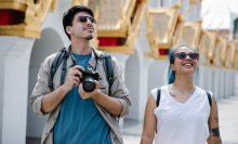 Two people sightseeing in sunglasses, one of them carrying a camera round their neck