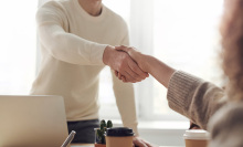 two people shaking hands over a table