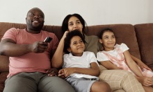 A family watching tv together on a couch.