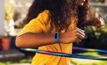 Child hula hooping while wearing blue Fitbit