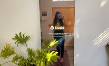 Person with long hair wearing black leggings and a yellow shirt standing in front of a Lululemon Studio Mirror