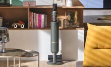 Green Samsung stick vacuum on dock in living space with shelves and furniture