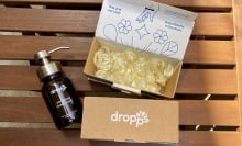 Dropps laundry detergent pod boxes and a hand soap bottle on a wood table
