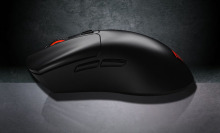 Black MOJO M2 wireless mouse resting lengthwise on a reflecting, gray surface.