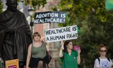 Pro-abortion protesters hold placards which read "abortion is healthcare" and "healthcare is a human right" during a counter-protest on abortion rights at Parliament Square, London.