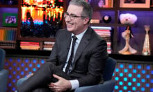 John oliver sitting on a talk show in a chair