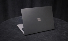 A greyish Microsoft Surface Laptop 2 on a dark, circular tabletop