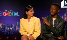 Sat against a purple  'Elemental' backdrop, Leah Lewis smiles at co-star Mamoudou Athie as he gesticulates