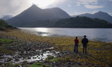 Two people stand on a beautiful Scottish loch.