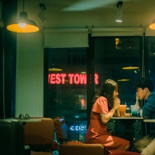 couple sitting across from each other in a diner booth sharing a milkshake