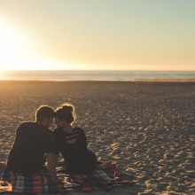 couple sitting on a blanket together on the beach