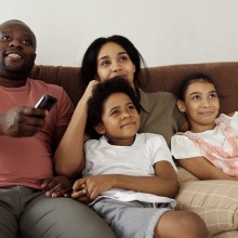 A family watching tv together on a couch.