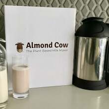 Almond cow machine next to cups of non-dairy milks