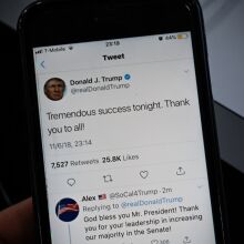 A photo of a phone displaying a tweet from Donald Trump's Twitter account in 2018, reading "Tremendous success tonight. Thank you to all!"