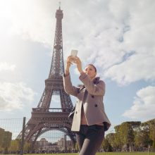 Female solo traveler make photo of Eiffel tower with smartphone while sightseeing in Paris