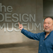Ai Weiwei faces the camera as he flips a middle finger in front of London's Design Museum in reference to his famous photographs.