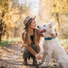 Woman petting dog standing on lush green path