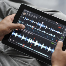person is holding ipad with a music editing software on screen