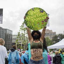 A demonstrator with "My! Body! My! Choice!" written on her torso protests the Supreme Court ruling to overturn the Roe v Wade decision, holding above her head a circular green sign that reads, "Grow abortion power"