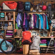 Outdoor clothing, bikes, coolers, and more outdoor gear hanging on wall