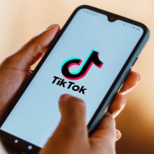 A person holding a phone with the TikTok logo.