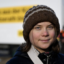 Thunberg stares into the camera wearing a brown beanie.