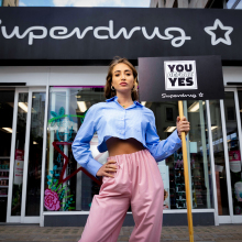georgia harrison holding a sign that reads "you before yes" in front of a superdrug