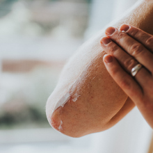 Close up of person hand applying lotion to their forearm