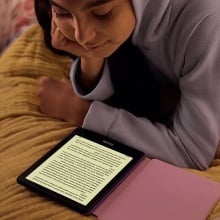 person reading kindle paperwhite kids on their bed
