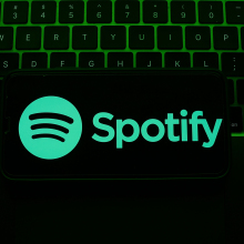A laptop keyboard and Spotify logo displayed on a phone screen are seen in this illustration photo.