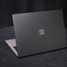 A greyish Microsoft Surface Laptop 2 on a dark, circular tabletop