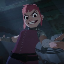 A young girl with pink hair grins, exposing fangs, and extends her hands in a big gesture.