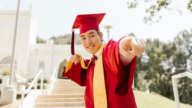 a man in red academic regalia smiling while wearing mortarboard