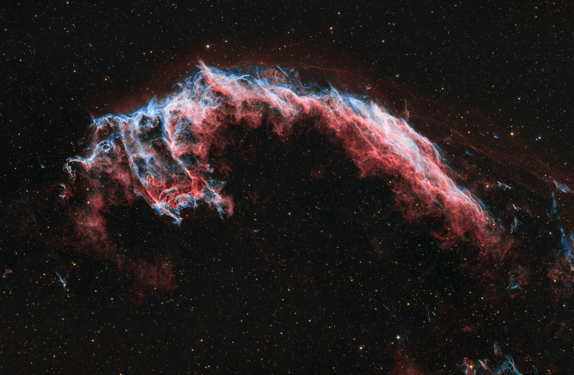 A red and blue nebula visible in a black sky.