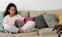 girl sitting on couch looking at tablet