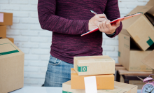person checking list and packing boxes in warehouse