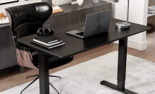 black adjustable desk in an office with black office chair behind it