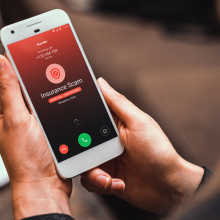 a woman holding an iphone receiving a call that's flagged as spam by the truecaller app
