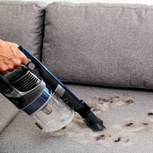 Shark vacuum picking up debris on a sofa