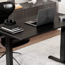 black adjustable desk in an office with black office chair behind it