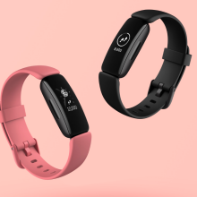 Two Fitbit Inspire 2 fitness trackers on pink background