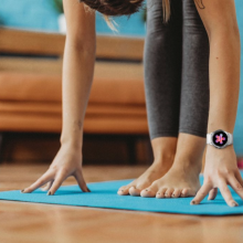 hands reaching down on yoga mat with visible smartwatch on left wrist
