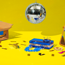 a disco ball above a pile of jewelry and an amazon box against a bright yellow background