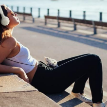 woman sitting on a bench overlooking the beach wearing white headphones