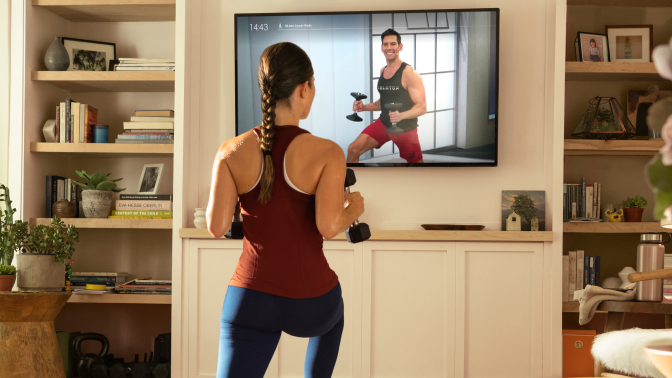 woman standing in front of a TV playing a workout video