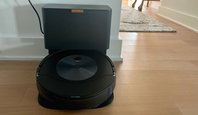 Roomba on hardwood floor with hallway and table in background